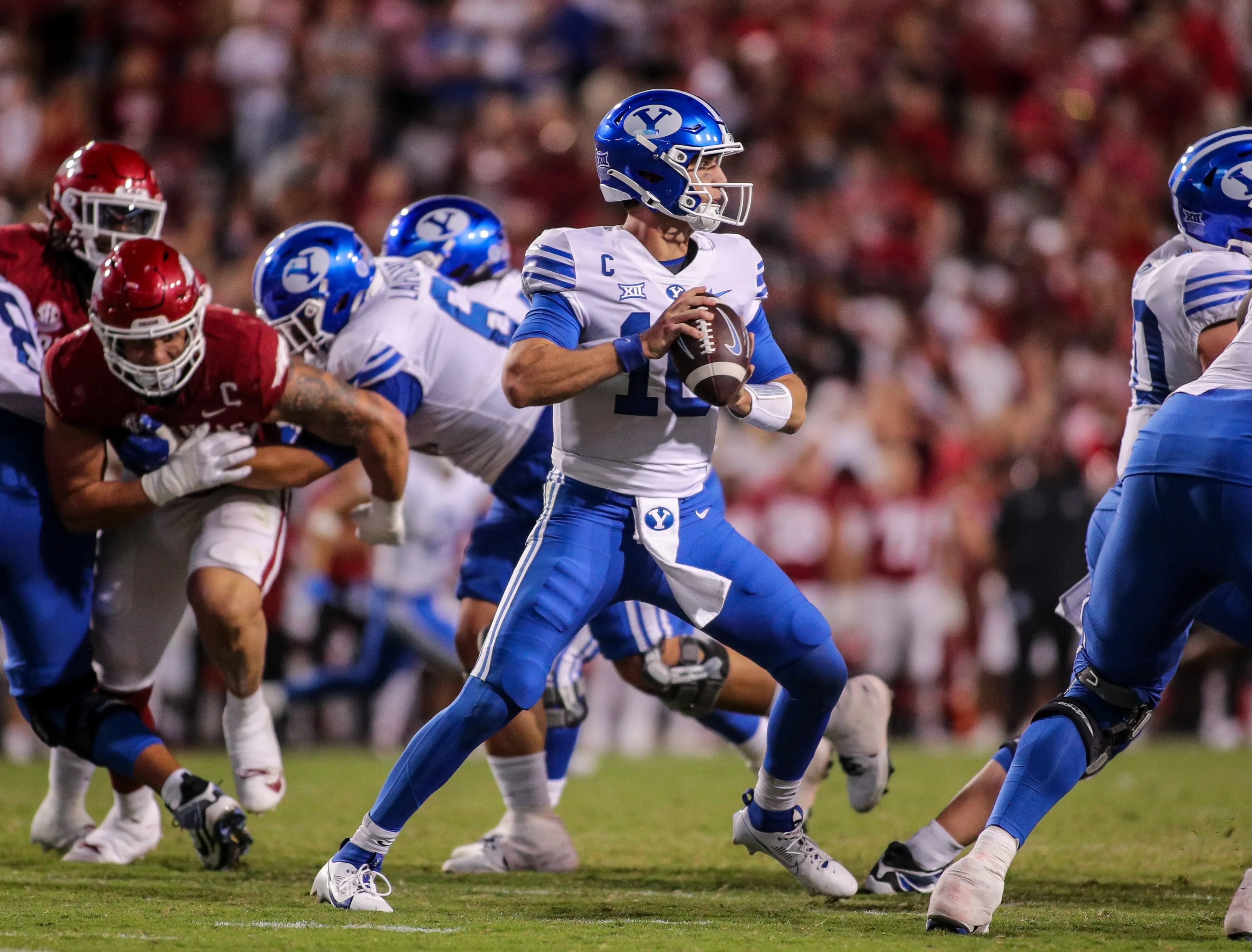 BYU quarterback in blue uniform preparing to throw during a college football game against a team in red