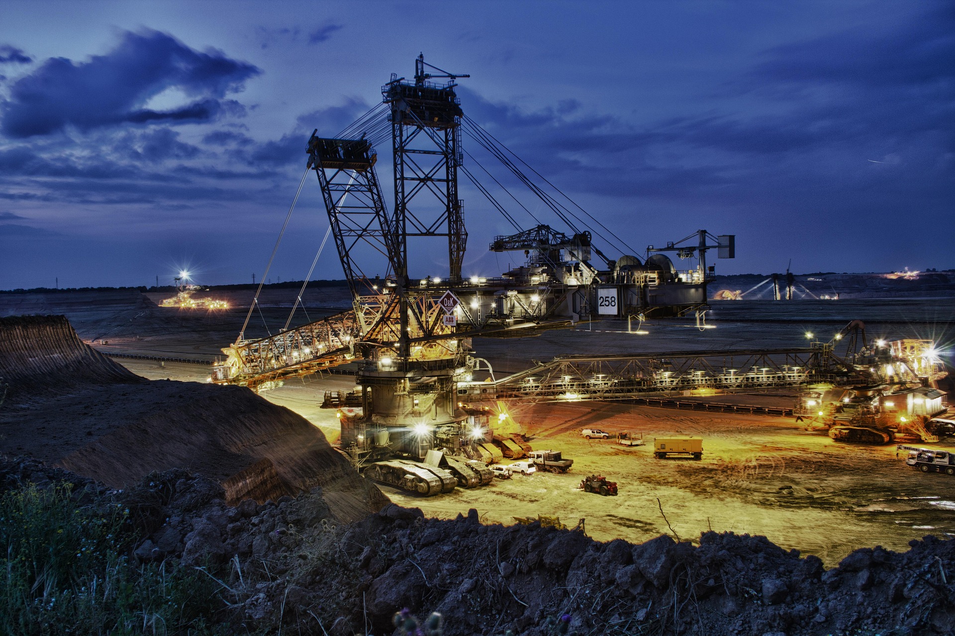 Large industrial bucket-wheel excavator operating at an open-pit mine illuminated at twilight