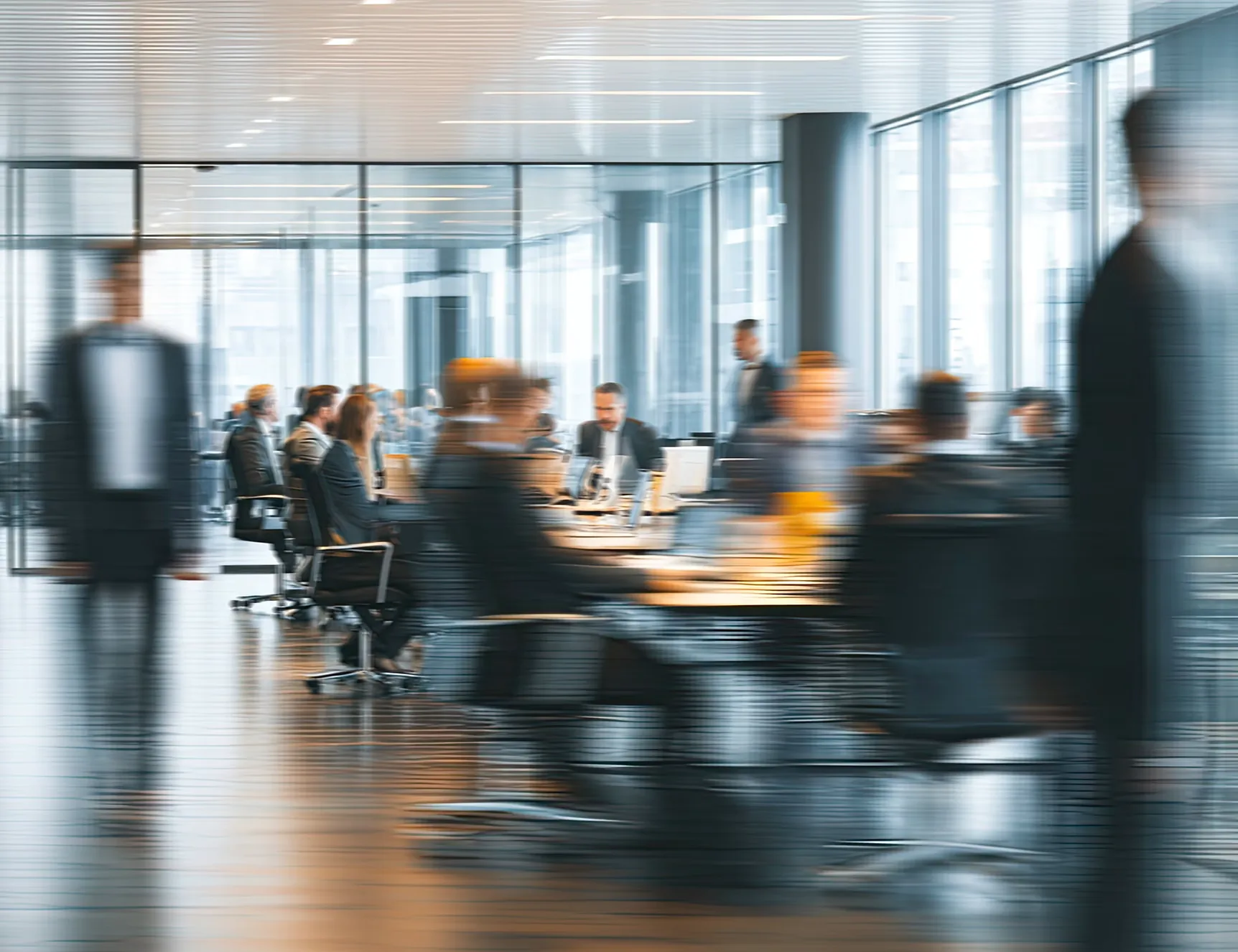 Motion-blurred professionals moving through a glass-walled corporate conference room during a busy meeting