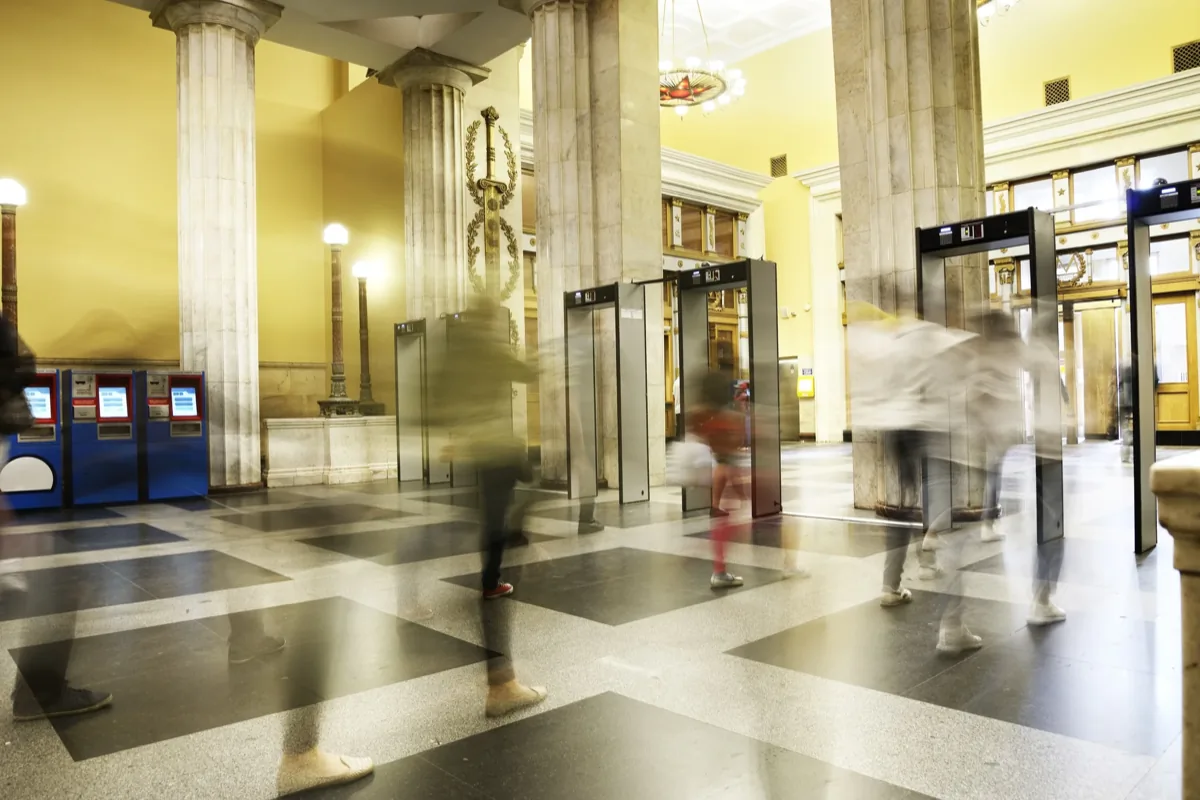 Motion-blurred people walking through a grand bank lobby with marble columns and checkered floors