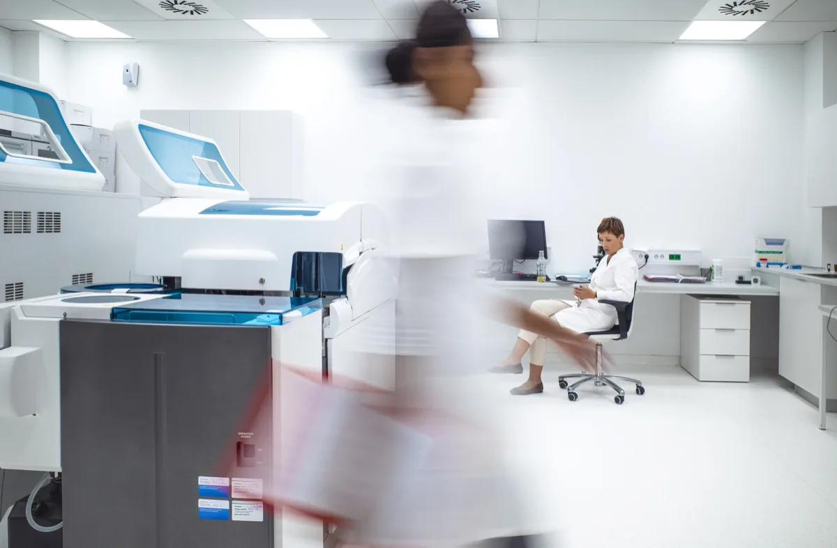 Scientists working in a modern laboratory with analytical equipment, one seated at a desk, another in motion blur